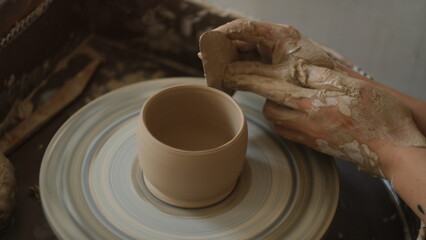 Fototapeta na wymiar male hands make a jar on a potter's wheel