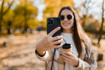 attractive young woman walking in autumn wearing jacket using phone