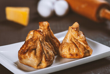 Georgian fried Khinkali dumplings with meat in white plate on wooden table. Traditional dish of Caucasian cuisine.