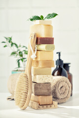 Stack of assorted natural soap bars on white bathroom countertop