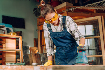 Young woman wearing protective glasses working in the workshop