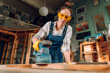 Young woman wearing protective glasses working in the workshop - obrazy, fototapety, plakaty
