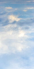 Bright sky with white and blue clouds, vertical format