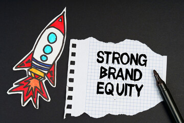 On a black background, a rocket, a marker and paper with the inscription - STRONG BRAND EQUITY.