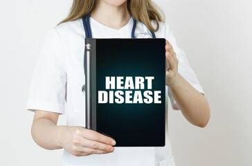 Fototapeta na wymiar The doctor is holding a tablet with the inscription - HEART DISEASE