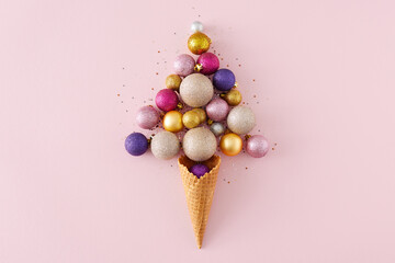 Top view photo of christmas tree balls and sequins flying out of ice cream cone on isolated pastel...
