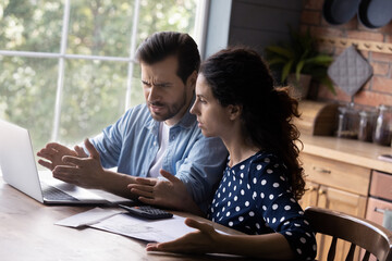 Unexpected debt. Worried married couple do financial paperwork discuss overdue bill have online...