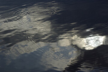 The sun's rays are breaking through the black cloud. Reflection in water.