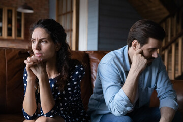 Marital split. Depressed young husband wife sit on sofa turn backs to each other feel upset empty think of separation divorce. Stubborn selfish spouses demonstrate indifference after family dispute - obrazy, fototapety, plakaty