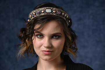 Portrait of a young girl on a dark blue background in a beautiful headdress