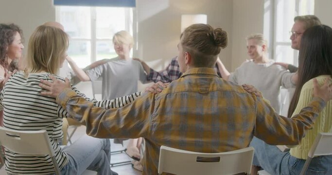 Close Up Group of Diverse People Put Hands on Shoulders, Sitting in a Circle During the Psychological Therapy, Feeling Support from Each Other.
