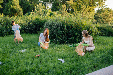 A group of girls with children at sunset are engaged in garbage collection in the park....