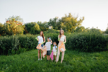 A group of girls with children at sunset are engaged in garbage collection in the park....