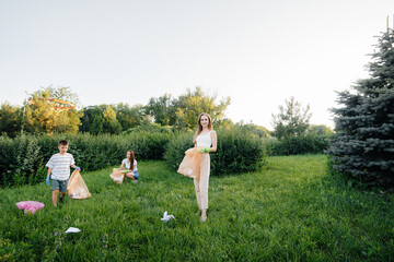 A group of girls with children at sunset are engaged in garbage collection in the park....