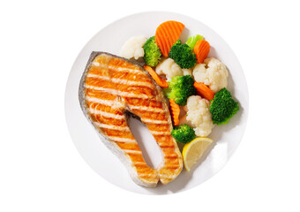 plate of grilled salmon steak with vegetables isolated on white background