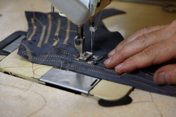 Professional overlock industrial sewing machine in shoemaker workshop. Equipment for edging,...