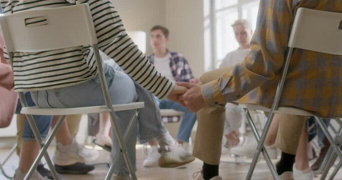 Close Up Group of Diverse People Holding Hands and Sitting in a Circle During Group Therapy. Feeling Support from Each Other.
