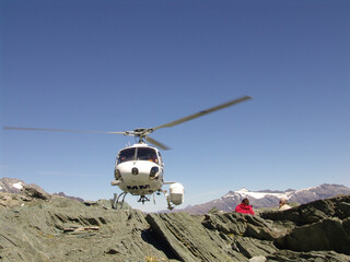 People watching as a helicopter arrives or takes off on a mountain