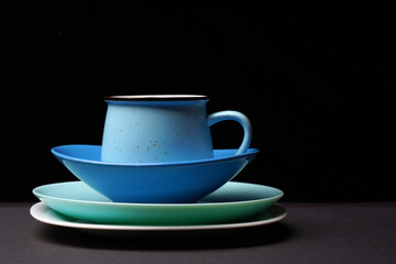 Ceramic plates of white, turquoise, blue and blue colors stand in a pile. On top of the mug.
