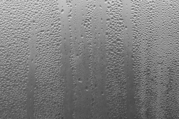 Raindrops on the window pane on a gray background. Natural pattern of raindrops. Texture for creativity. Water on the surface of the glass.