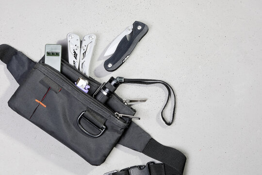 Wearable set for survival and tourism, every day carry, in flat lay on gray background, with copy space