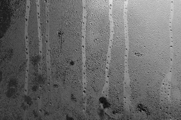 Raindrops on the window pane on a gray background. Natural pattern of raindrops. Texture for creativity. Water on the surface of the glass.