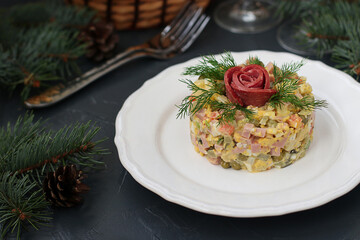 Festive salad Olivier with sausage, peas and potatoes on a white plate on gray background