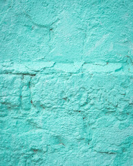 Fototapeta na wymiar Turquoise blue brick wall detail texture background. Old, painted, weathered and cracked stone bricks with concrete and stucco. Village house wall. Colorful backdrop for design. Vertical, copy space