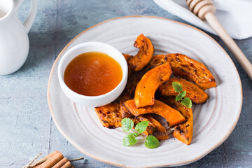 Baked pumpkin slices ready to eat and honey on a plate on the table. Vegetarian food. Thanksgiving Day. Close-up