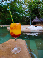 Mango Daiquiri alcohol coctail in pool. Tropical evening