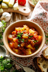 Vegetable zucchini and pumpkin stew sprinkled with fresh parsley in a ceramic bowl, top view