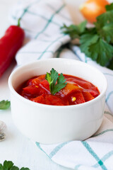 lecso national dish of Hungarian cuisine with pepper and tomato, greens on the white bowl. lecho of tomatoes and sweet paprika on the table. Hungarian food. copy space. vertical