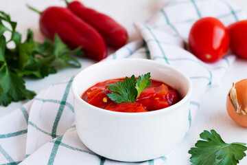 close-up lecso national dish of Hungarian cuisine with pepper and tomato, greens on the white plate. lecho of tomatoes and sweet paprika with ingredients on the table. Hungarian food. copy space.