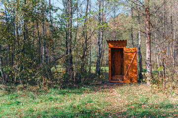 Fototapeta premium Opened wooden WC toilet cabin in a golden forest national park , close-up. Autumn landscape. Seasons, ecology, ecotourism, environmental conservation, architecture