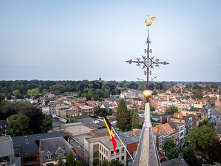 Top view of church and cross at roof with Belgian flag hanging and overlooking urban area of Edegem near the city of Antwerp