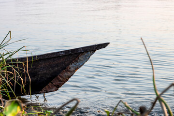 Parked old abandoned wooden boat at the river bank close up