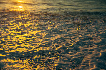 Foam of the surf during sunset on the coast of the Atlantic Ocean.