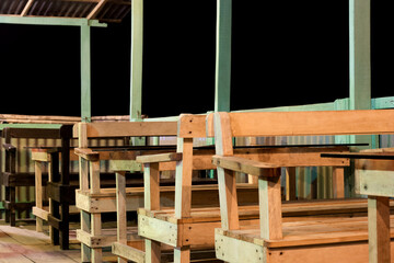 A row of wooden chairs and tables inside of a cafe close up