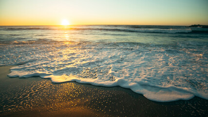 A beautiful sunset on the Atlantic coast with foamy surf.