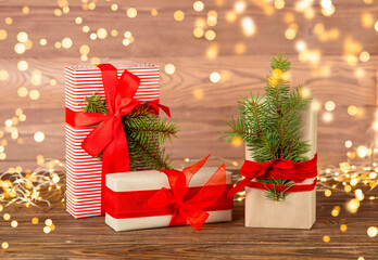 Christmas postcard gifts packed in kraft paper with a red ribbon on a wooden table. Defocus.
