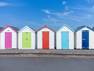 Fototapeta na wymiar Colourful beach huts and blue sky with few clouds in the English seaside town of Devon, UK