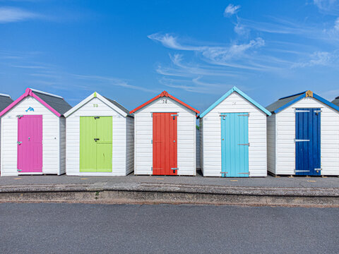 Colourful beach huts and blue sky with few clouds in the English seaside town of Devon, UK