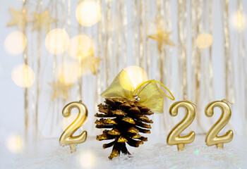Number 2022 gold color and cone with golden bow, bokeh, golden background and stars. Concept of Christmas, new year.