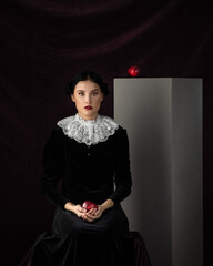 Studio portrait of pretty woman dark hair, white collar. Face, Thinking. Hold red apple. Dark...