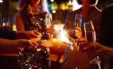 Sparkling sparklers in the hands. Playing firework to celebrate winter holidays with friends at the party. Magic New Year, Christmas.