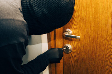 a man in a black balaclava and gloves breaks into the apartment