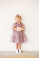 Little white Birthday girl with cake in a pink dress laughs. Preschooler. 