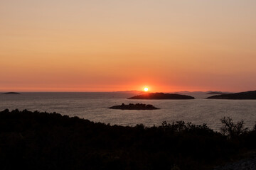 Golden, summer sky during amazing sunset over Kornati islands observed from the hill above small tourist town of Rogoznica, Croatia