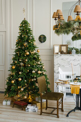 Fototapeta na wymiar Christmas tree with golden balls in the living room by the marble fireplace and table with chairs