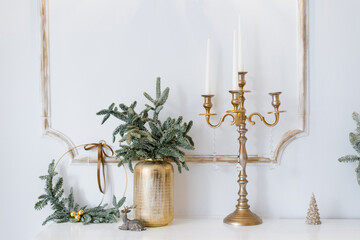 Christmas decor in a classic living room or bedroom in bright colors. Spruce branches in gold vases with toys and a gold candlestick on the dresser